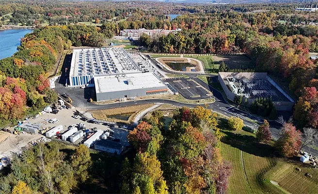 NY-Data-Center Ban Aerial view of DataBank's LGA3 data center campus in Orangeburg, N.Y., with electrical infrastructure and surrounding wooded landscape.