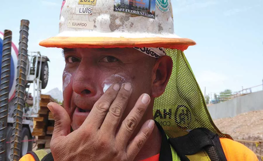 Construction tradesworker applies sunscreen