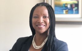 Portrait of Lakisha Woods, wearing a navy blue suit jacket and pearl necklace
