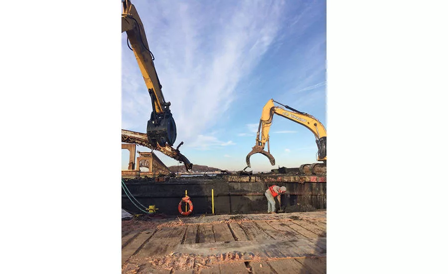 Crews working for subcontractor J.R. Vinagro Corp. load scrap on a work barge left over from demolition of 1950s-era bridges over Boston Harbor