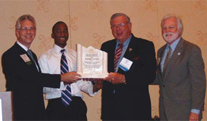 Leonard Toenjes, president of AGC of St. Louis (left) and Brandon Dyer, 2009 Construction Careers Center graduate (second from left) help display the Founder’s Award. 