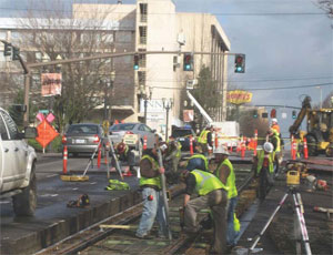 Crews working on the newest phase of the Portland Streetcar Loop project first saw cut an 8-ft swath out of the existing roadway and excavate down approximately 13 in. Then crews lay the rebar cage and align the track prior to pouring concrete.