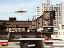 Crews erect steel grids below and above drum-shaped isolators (above, at right).