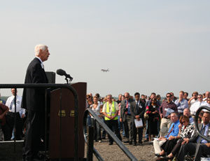 Jerry Roper, chief executive of the Chicagoland Chamber of Commerce, welcomes guests during a commissioning ceremony while a plane approaches new Runway 10L/28R. 