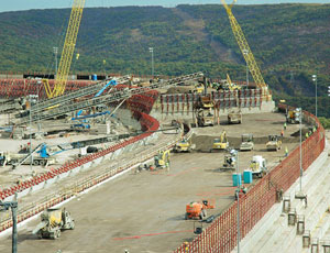 Roller-compacted concrete dam will replace earth-and-rockfill dam that failed, clearing forest from the mountainside (above).