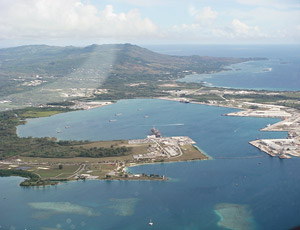 Guam’s Apra Harbor is planned as the site for deep-water port facilities to accommodate nuclear carrier ships, but the Navy is deferring a decision on a specific location until further study of likely environmental damage. 